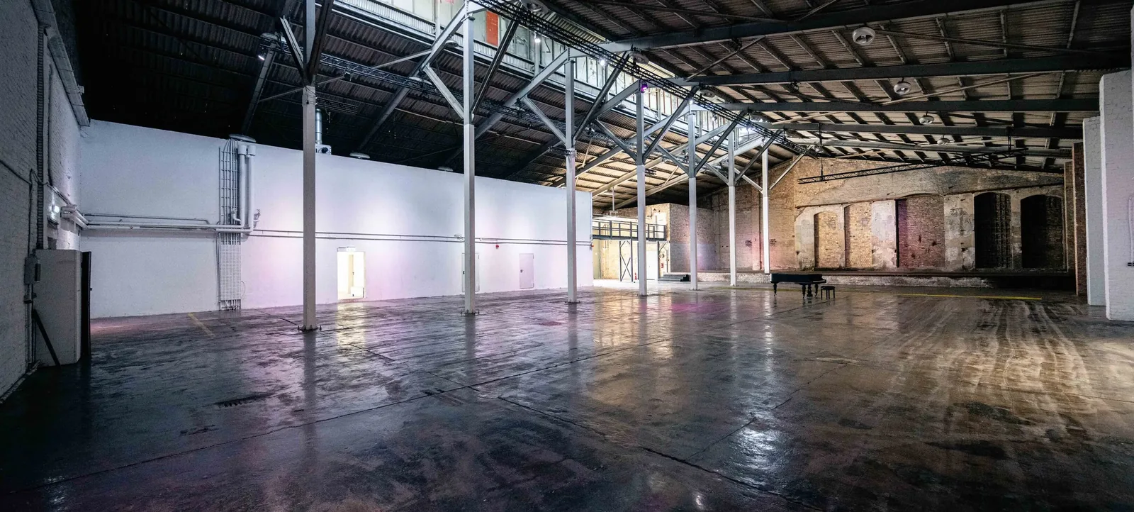Hauptsaal des Komplex mit Klavier und Backsteinwänden